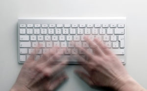 Person die an einer Tastatur schreibt