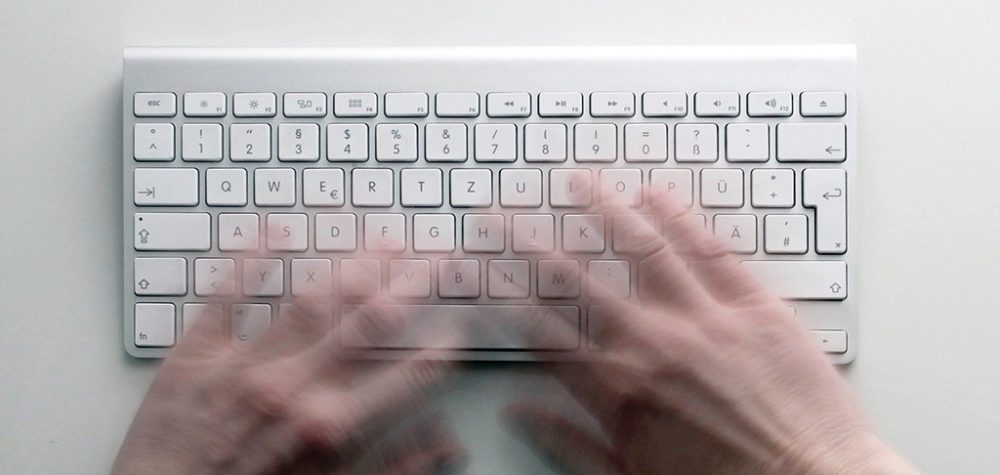 Person die an einer Tastatur schreibt